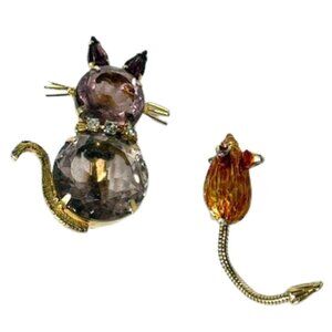 Metal and light purple cat and gold-tone mouse brooches.